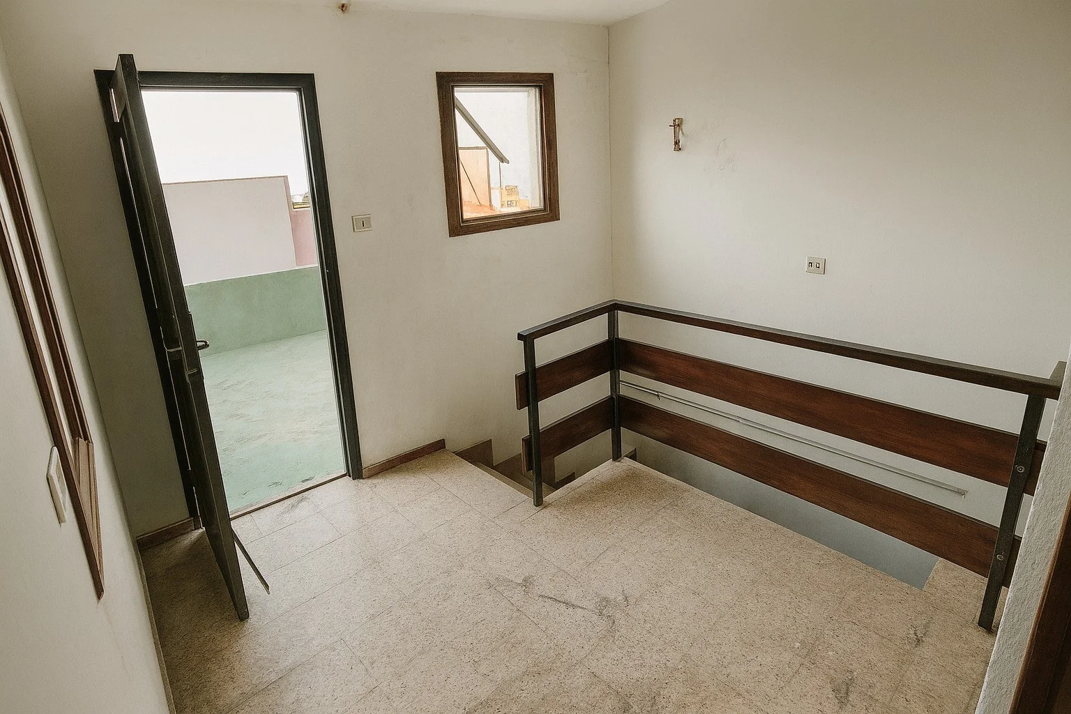 Descansillo con barandilla de madera y puerta al exterior.